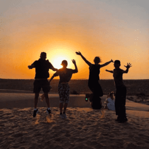 india group tour jumping in the air at sunset in the Thar desert